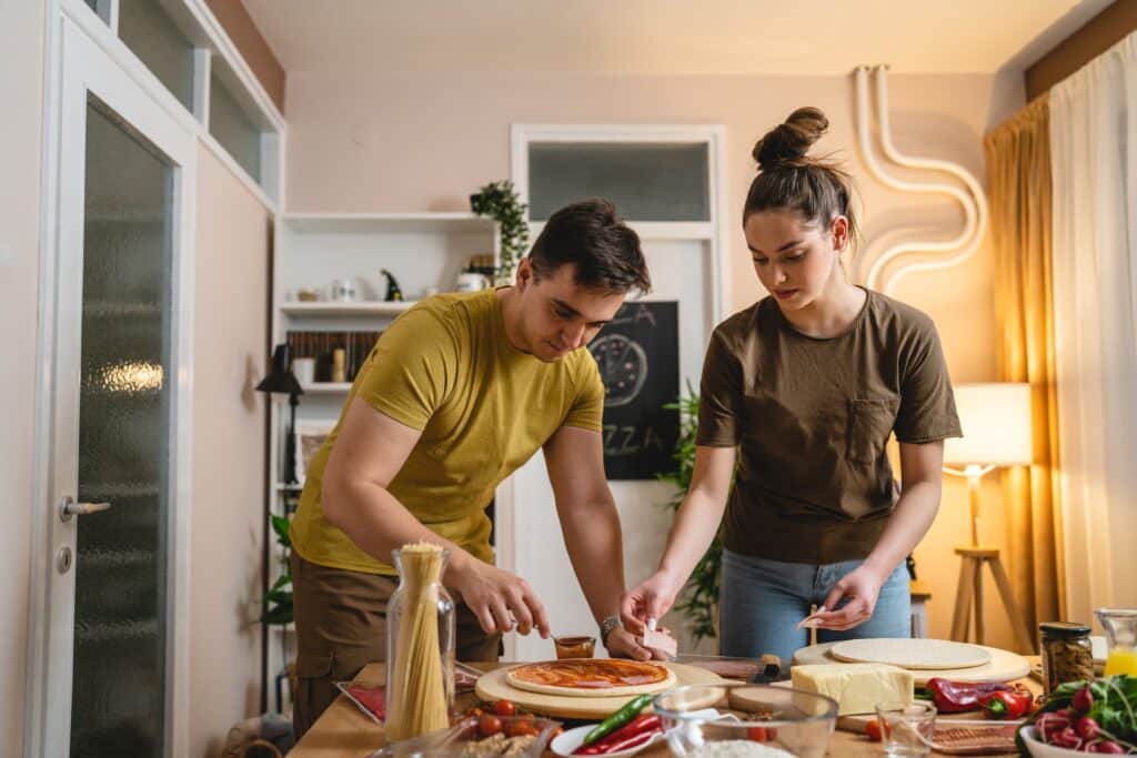 Young couple making pizzas at home - Pivotal Leaders