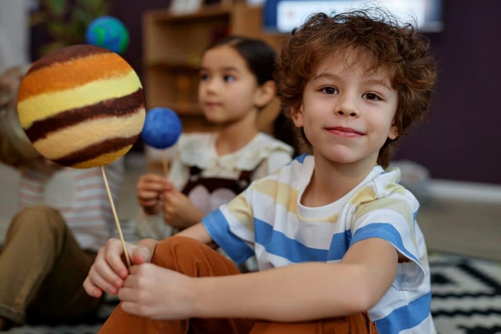 cute-little-kid-holding-planet-model-smiling-camera-preschool-class